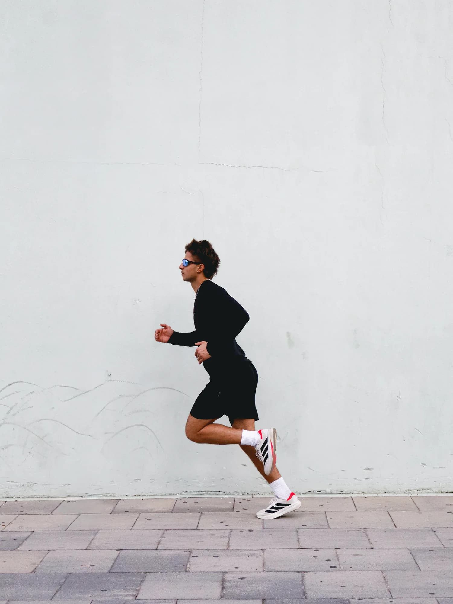 Persona corriendo al aire libre frente a un muro claro, fotografía del manual de marca Naovi