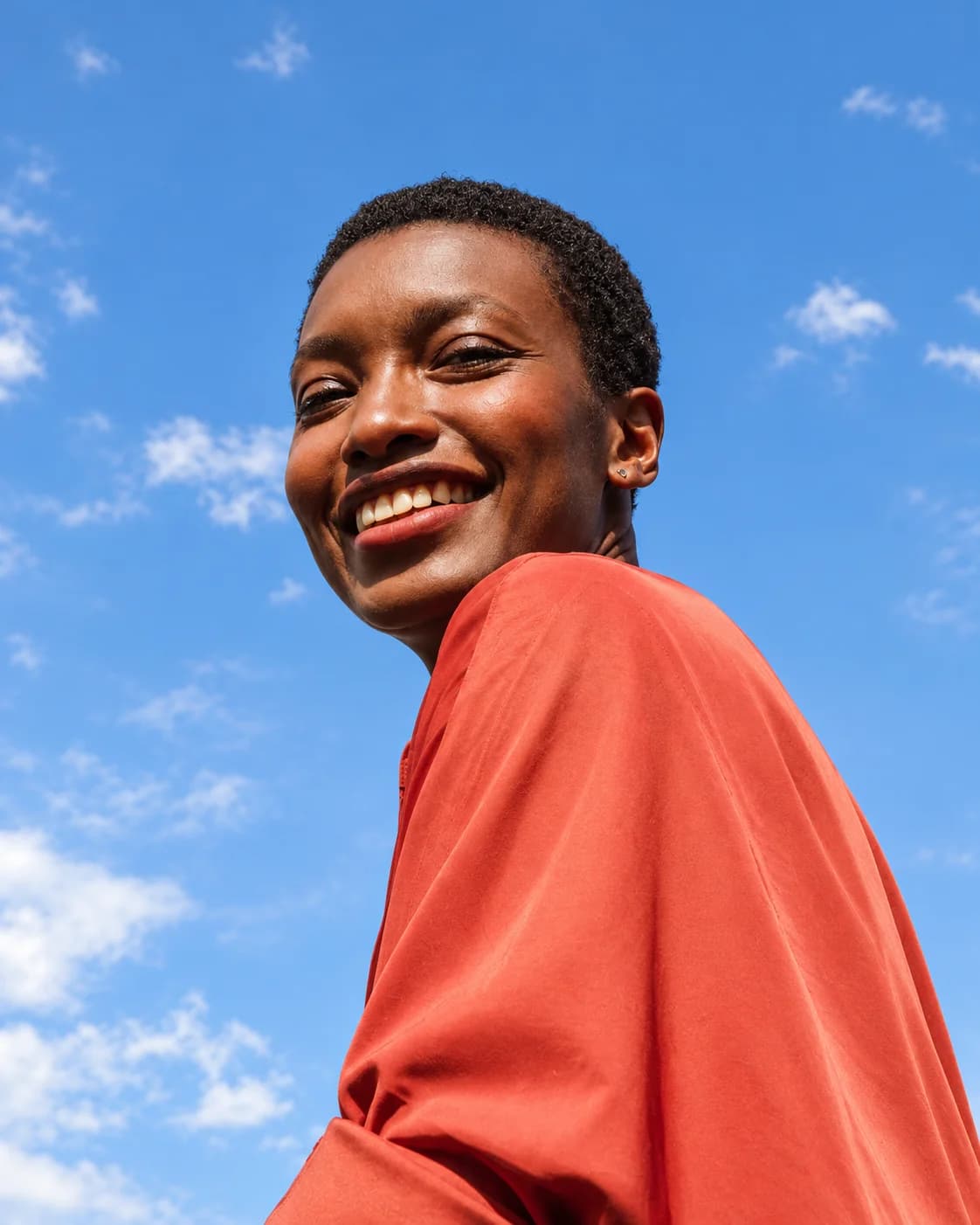 Mujer sonriente bajo el cielo azul, fotografía del manual de marca Naovi