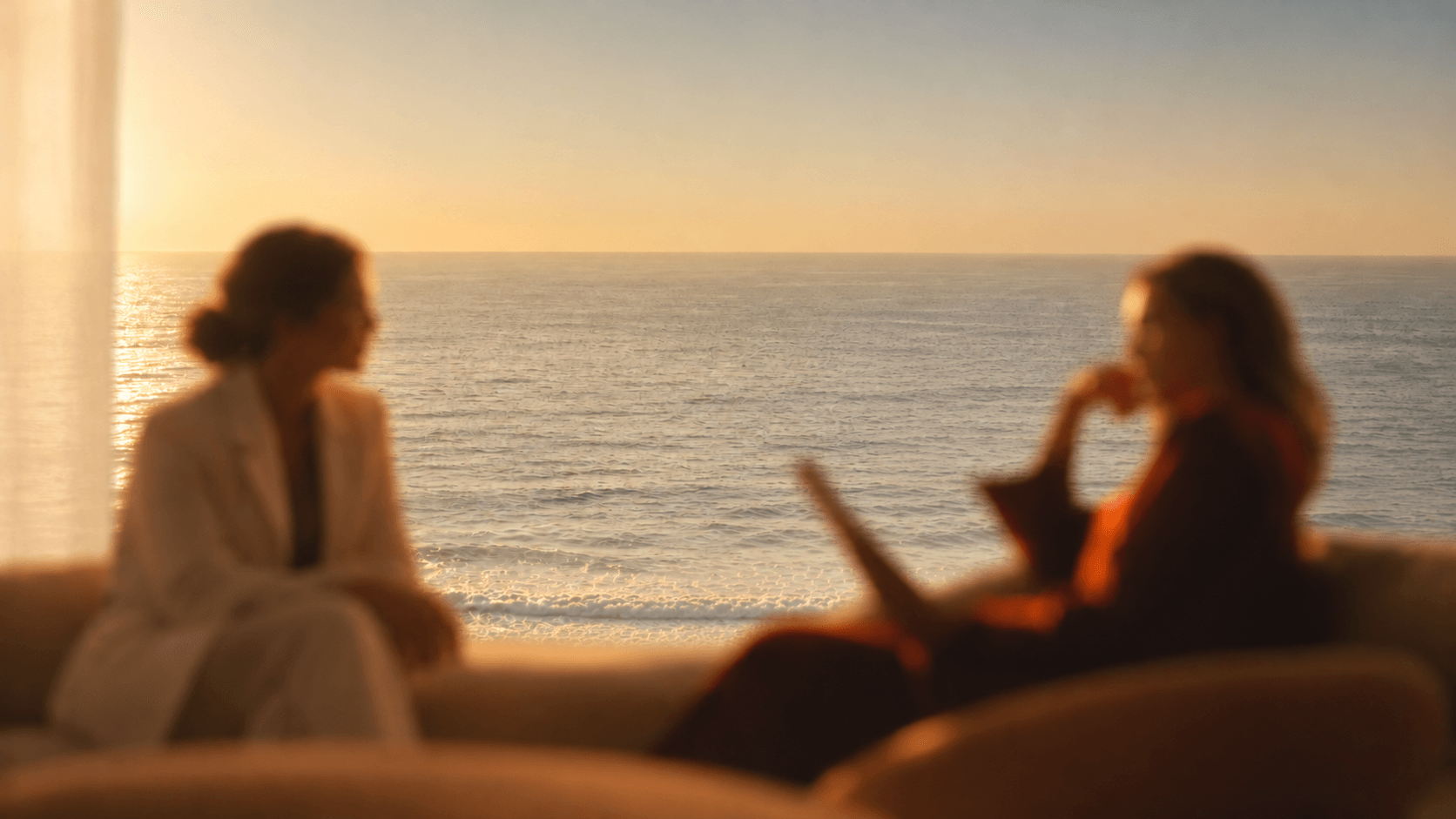 Doctora escuchando a una mujer junto al mar, con el desenfoque cálido del manual de marca Naovi